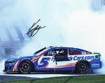 Autographed 8x10 glossy photo showing Kyle Larson in the midst of a dramatic burnout celebration after a race win, capturing the excitement of NASCAR racing and driver triumph.