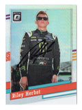 This autographed Riley Herbst 2024 Donruss Optic 1991 RETRO Silver Prizm Insert NASCAR card features a stunning silver prizm finish and a signature from the rising NASCAR star, making it a rare collectible.