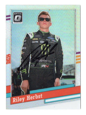 This autographed Riley Herbst 2024 Donruss Optic 1991 RETRO Silver Prizm Insert NASCAR card features a stunning silver prizm finish and a signature from the rising NASCAR star, making it a rare collectible.