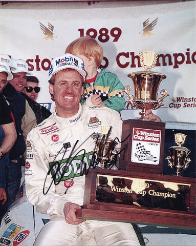 AUTOGRAPHED Rusty Wallace #27 Kodiak WINSTON CUP CHAMPION vintage 8x10 inch photo capturing the iconic Victory Lane moment of a racing legend Rusty Wallace, who clinched the championship. This historic photograph is autographed by Rusty Wallace and comes with a Certificate of Authenticity.